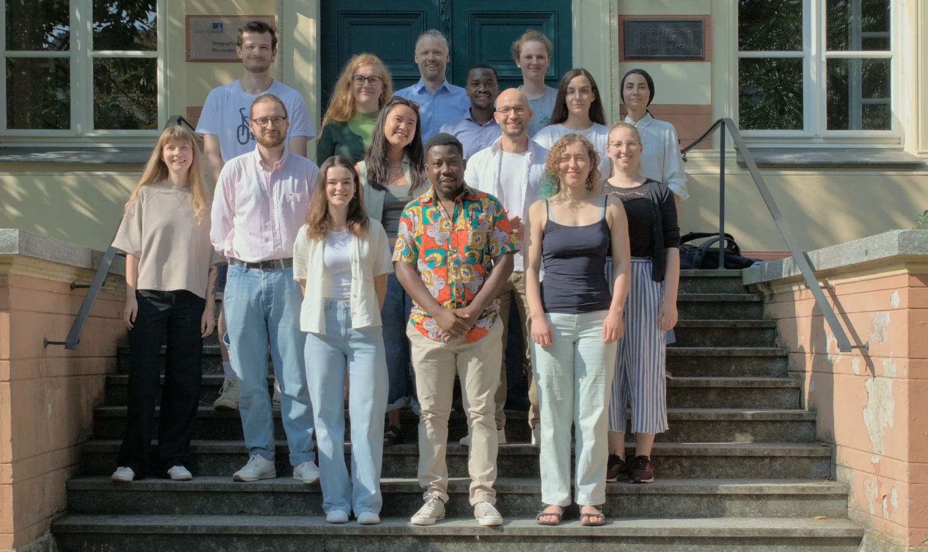 Mehrere Personen stehen auf einer Treppe vor einem historischen Gebäude.