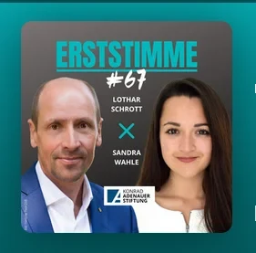 Eine Wissenschaftlerin und ein Wissenschaftler arbeiten hinter einer Glasfassade und mischen Chemikalien mit Großgeräten.