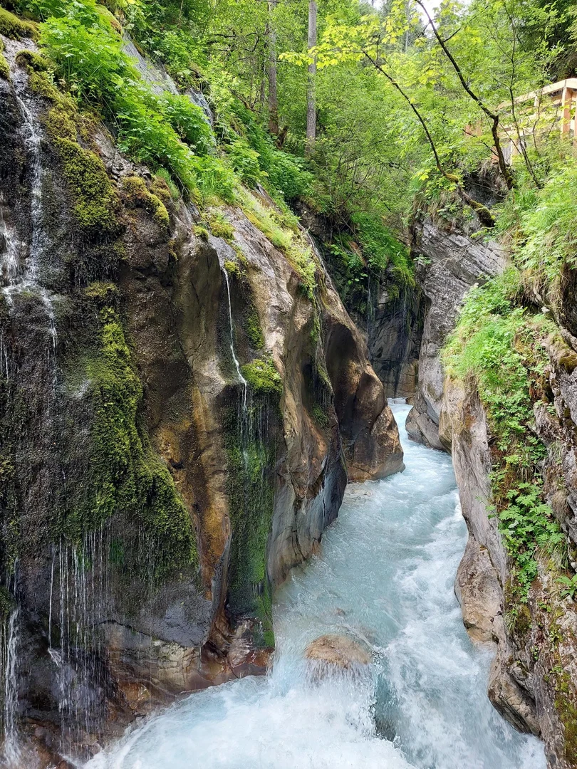 Eine Wissenschaftlerin und ein Wissenschaftler arbeiten hinter einer Glasfassade und mischen Chemikalien mit Großgeräten.