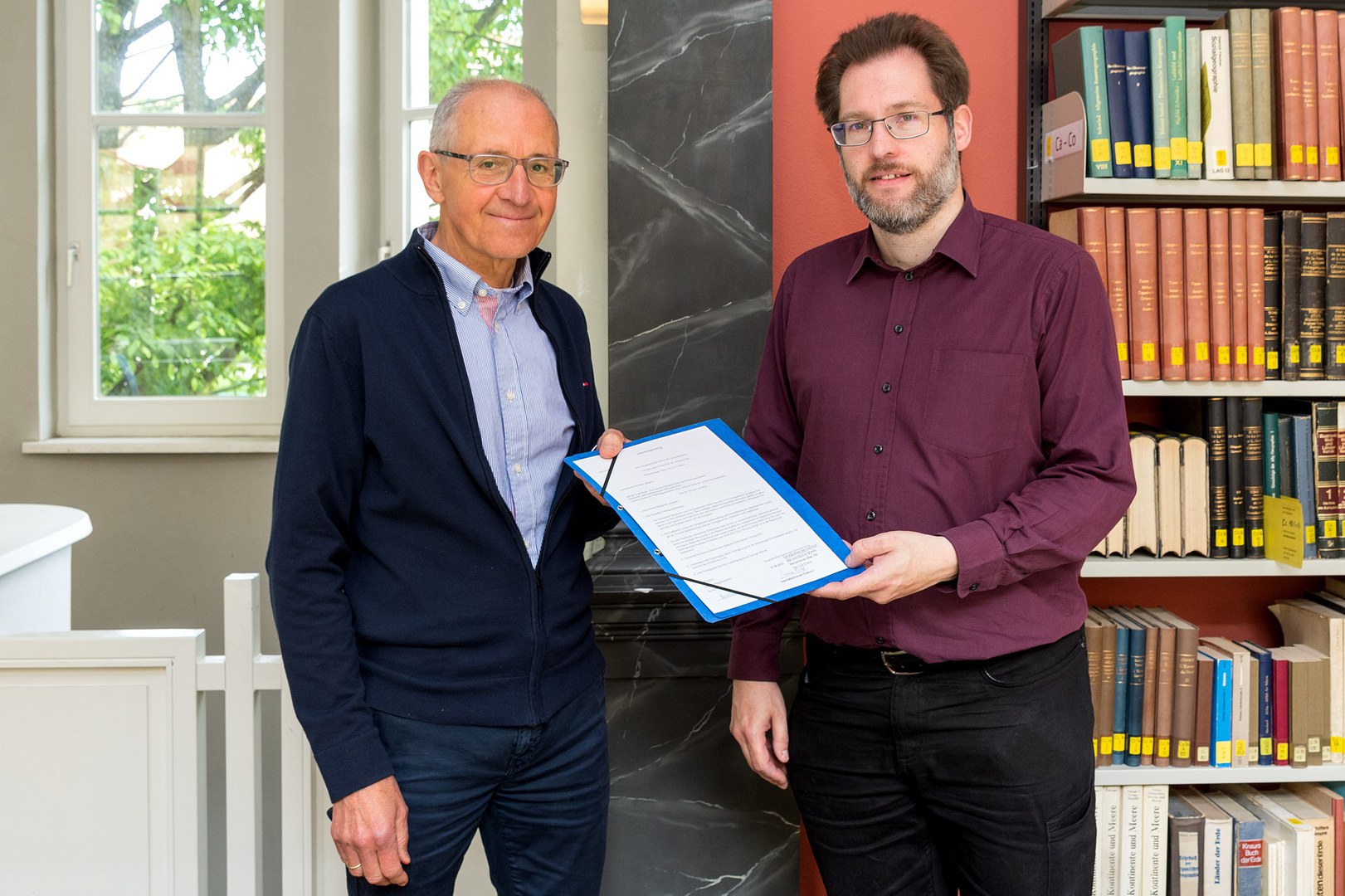 Prof. Nutz und Markus Ernzerhoff vom Stadtarchiv Bonn tauschen den Schenkungsvertrag aus.