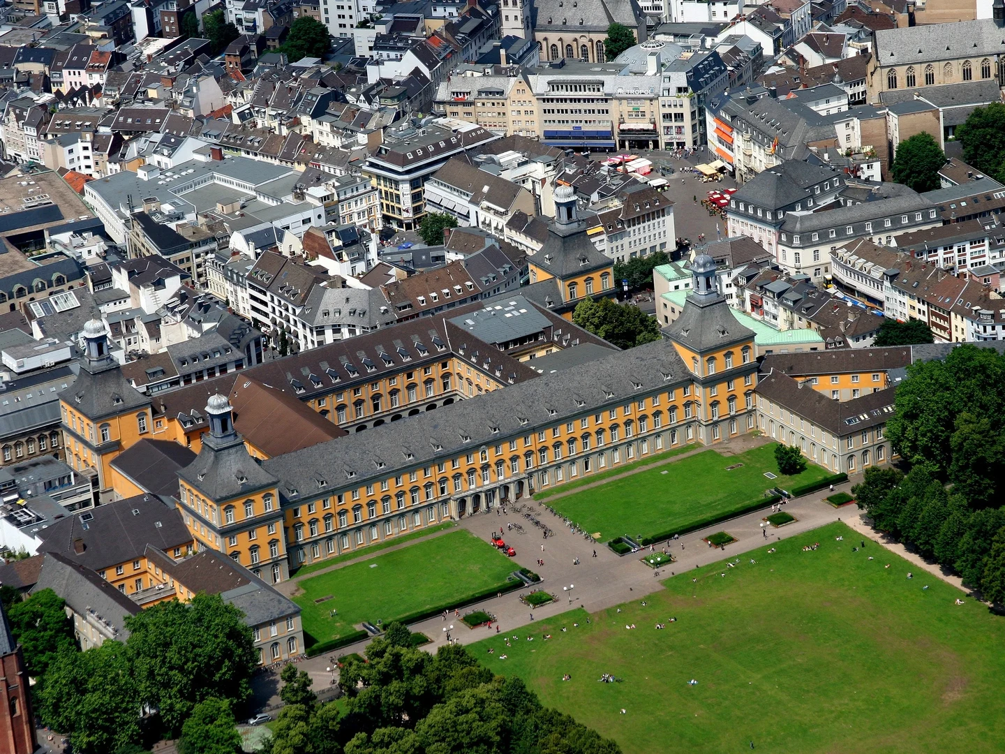 Eine Wissenschaftlerin und ein Wissenschaftler arbeiten hinter einer Glasfassade und mischen Chemikalien mit Großgeräten.