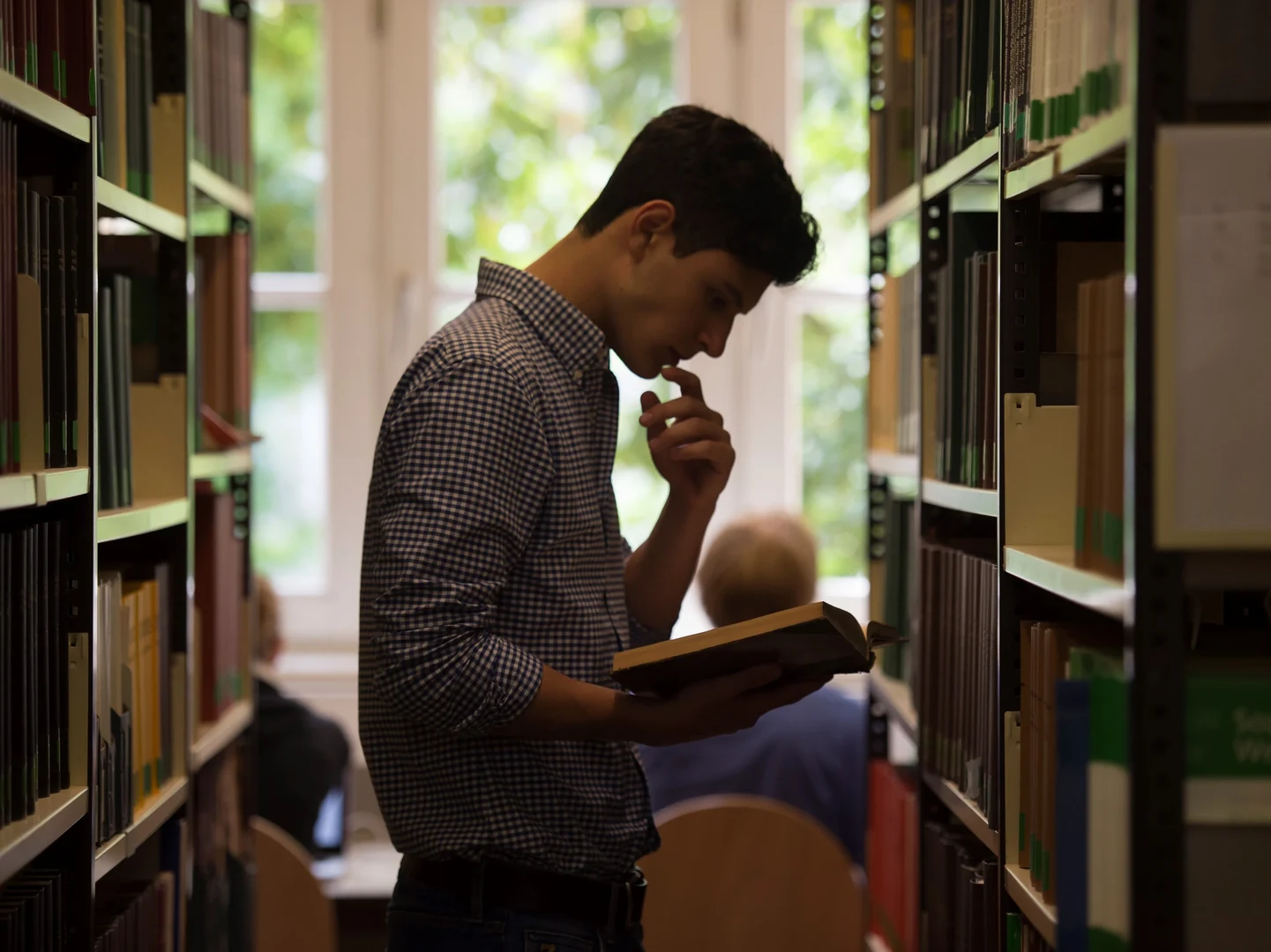 Ein Student liest sich in den Gängen der Bibliothek Literatur durch