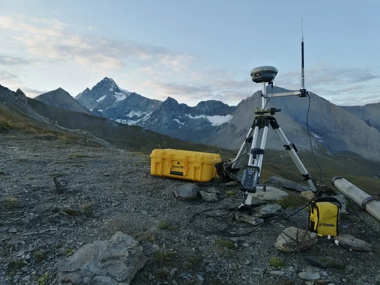 Eine Wissenschaftlerin und ein Wissenschaftler arbeiten hinter einer Glasfassade und mischen Chemikalien mit Großgeräten.